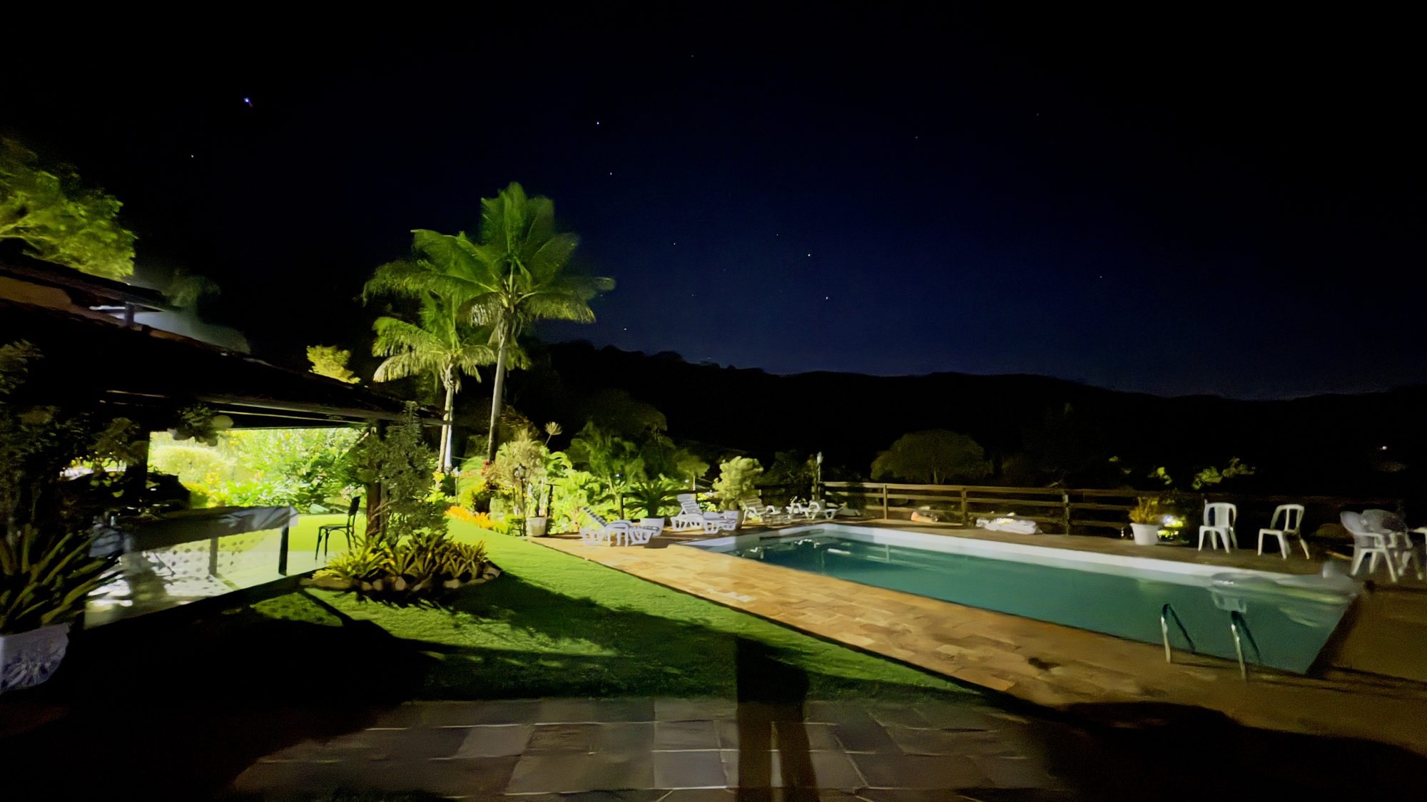 Piscina iluminada da casa ao anoitecer sob o céu estrelado da serra