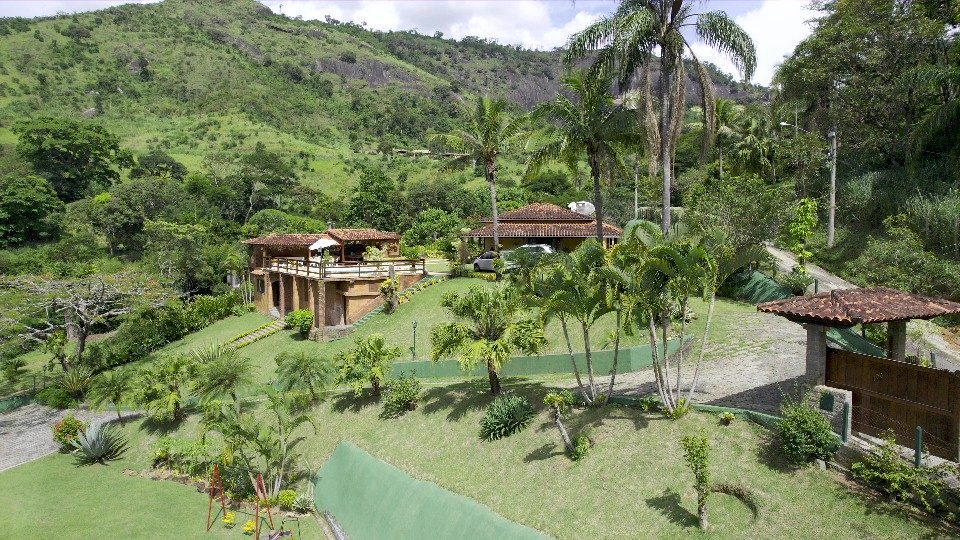 Casa entre palmeiras com montanhas verdes de Petrópolis ao fundo